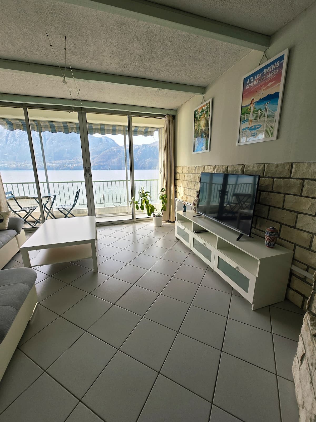 Séjour, meuble télé et balcon avec vue sur le lac